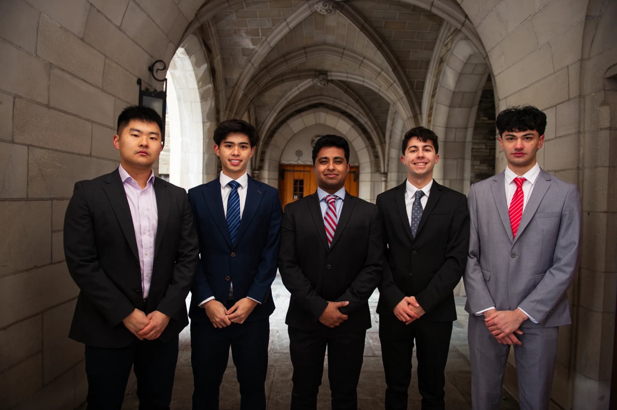 Five CPEC members in suits under a stone archway
